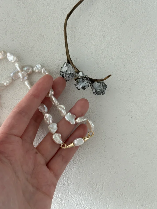 baroque pearl necklace held in hand for scale
