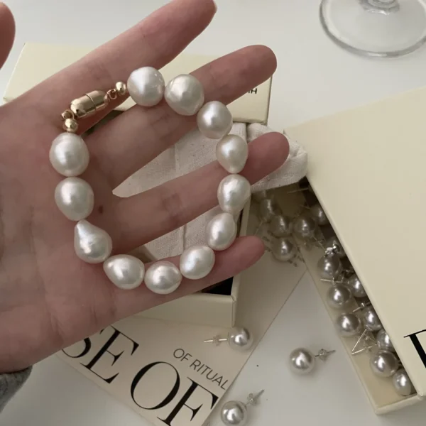 A model wearing a Baroque pearl bracelet with large mother-of-pearl beads, styled with a gold-plated clasp.