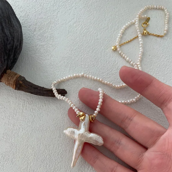 baroque pearl necklace cross pendant held in hand