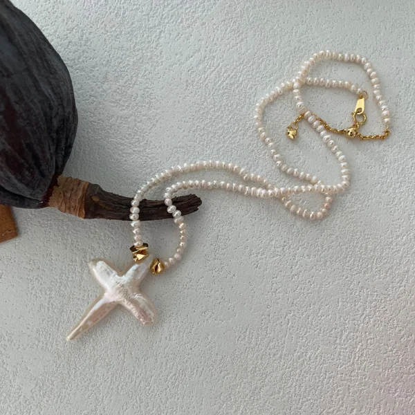 baroque pearl necklace with cross pendant on surface