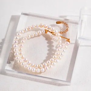 French Natural Pearl Necklace – Flat Lay French natural pearl necklace with gold extender on acrylic block