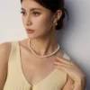 model styling French natural pearl necklace with hand to collarbone