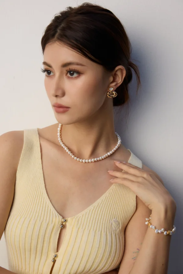 model styling French natural pearl necklace with hand to collarbone