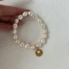 baroque freshwater pearl bracelet with gold coin charm held in hand