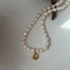 hammered yellow gold coin charm with tiny pearl on freshwater rosebud pearl necklace