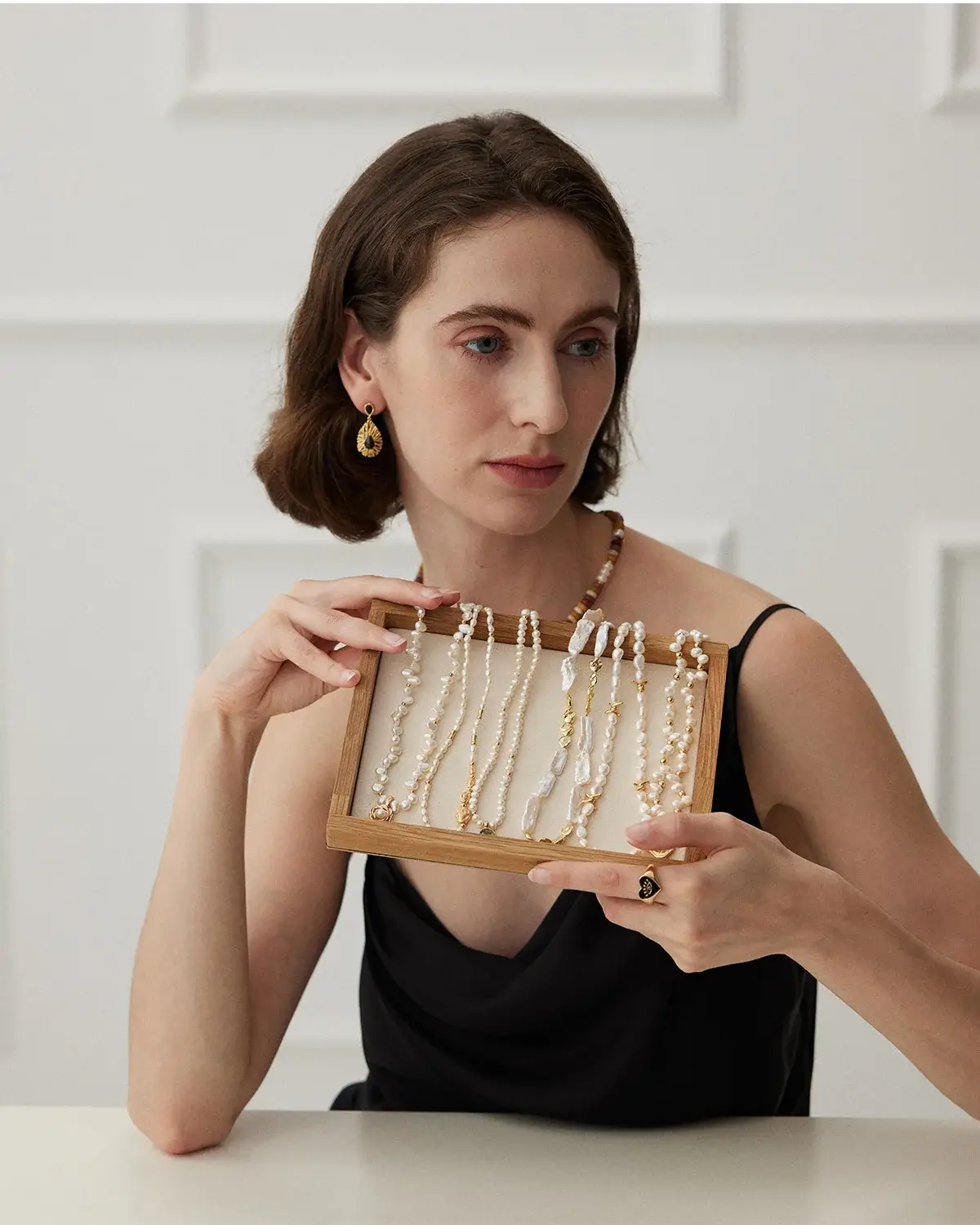 Woman wearing elegant freshwater pearl jewelry and holding baroque pearl necklaces