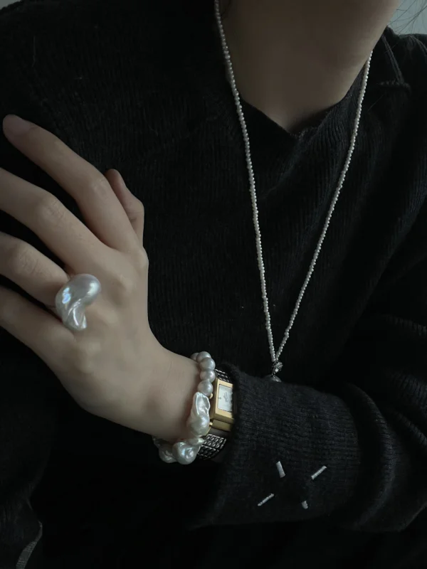 Baroque pearl bracelet styled with a pearl necklace and black sweater