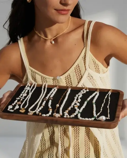 Woman wearing freshwater pearl jewelry and holding a tray of pearl necklaces for everyday styling