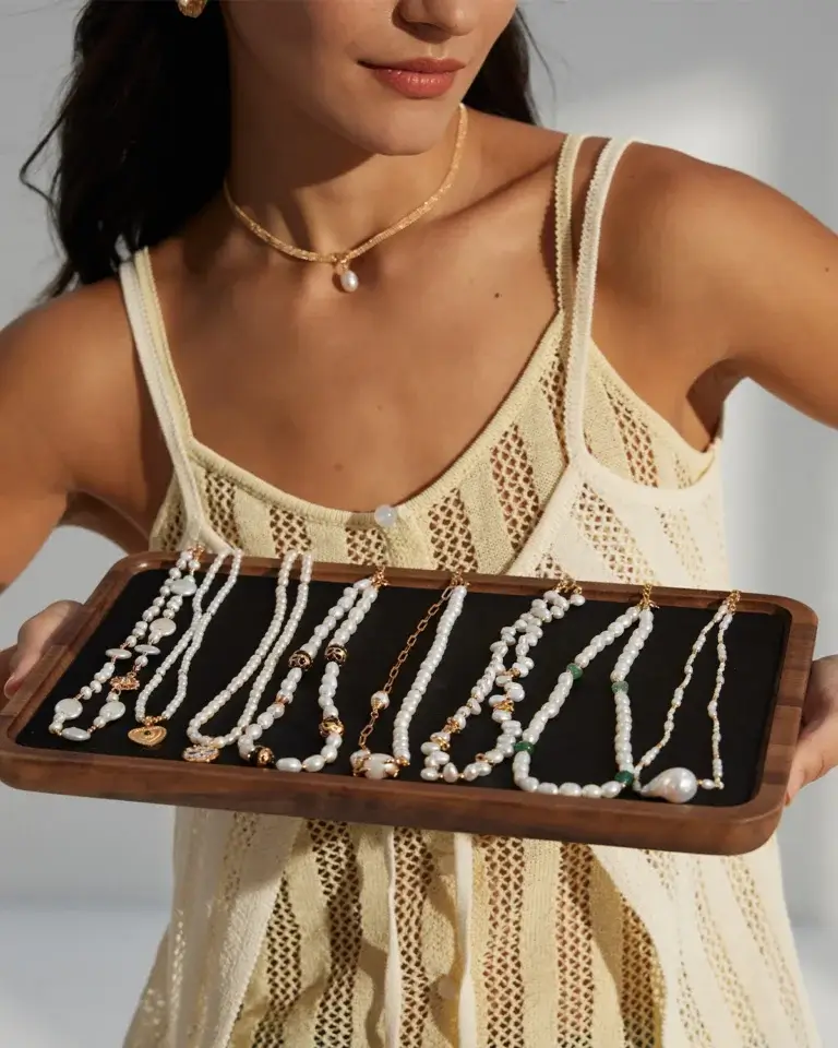 Woman wearing freshwater pearl jewelry and holding a tray of pearl necklaces for everyday styling