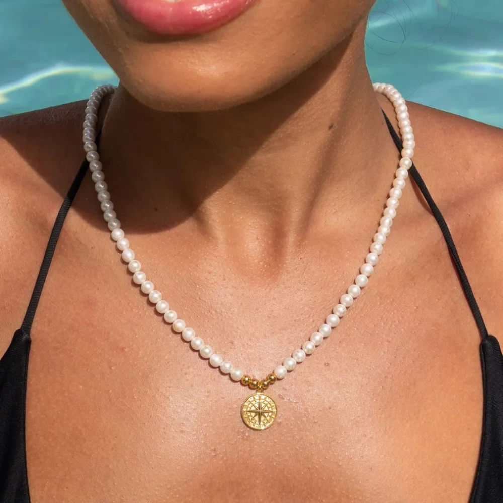 Pearl necklace with a round pendant worn near the upper chest
