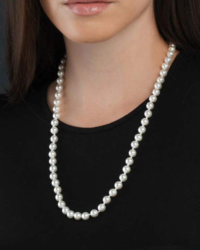 White pearl necklace worn over a black top as a pearl necklace length guide example