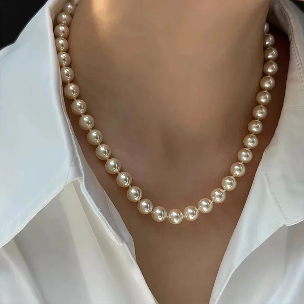 Pearl necklace worn near the collarbone with a white collared shirt
