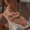 Model wearing two layered freshwater pearl necklaces with gold-tone details