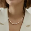 Aurora Freshwater Pearl Necklace Close-Up Close-up of a woman wearing a white 5.5–6mm freshwater pearl necklace