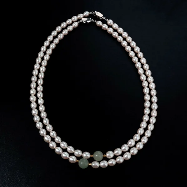 Full view of freshwater pearl necklaces with jade accent beads arranged on a black background