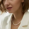 Freshwater Pearl Necklace Side-Wear Look Woman wearing a delicate white freshwater pearl necklace with a white blazer
