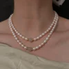 Layered white freshwater pearl necklaces with jade accent beads worn around the neckline